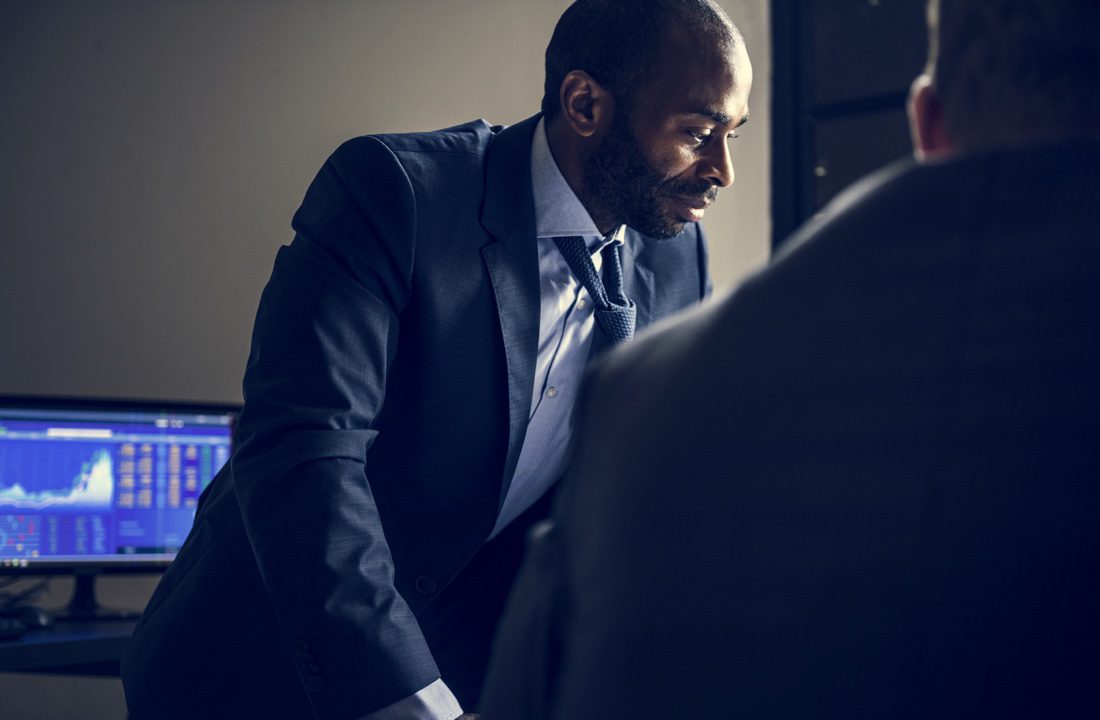 Two businessmen in suits looking at a computer screen.