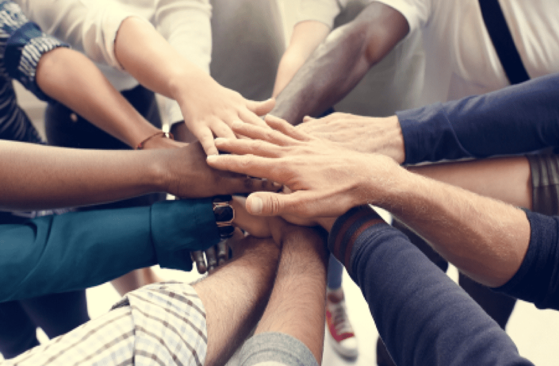 A group of people putting their hands together in a circle.