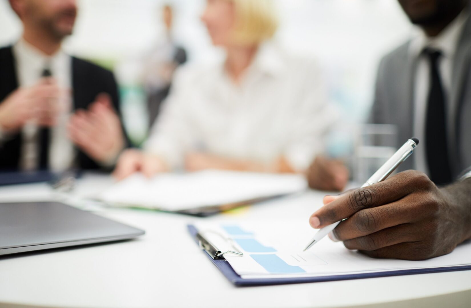 A group of business people sitting around a table with a pen.