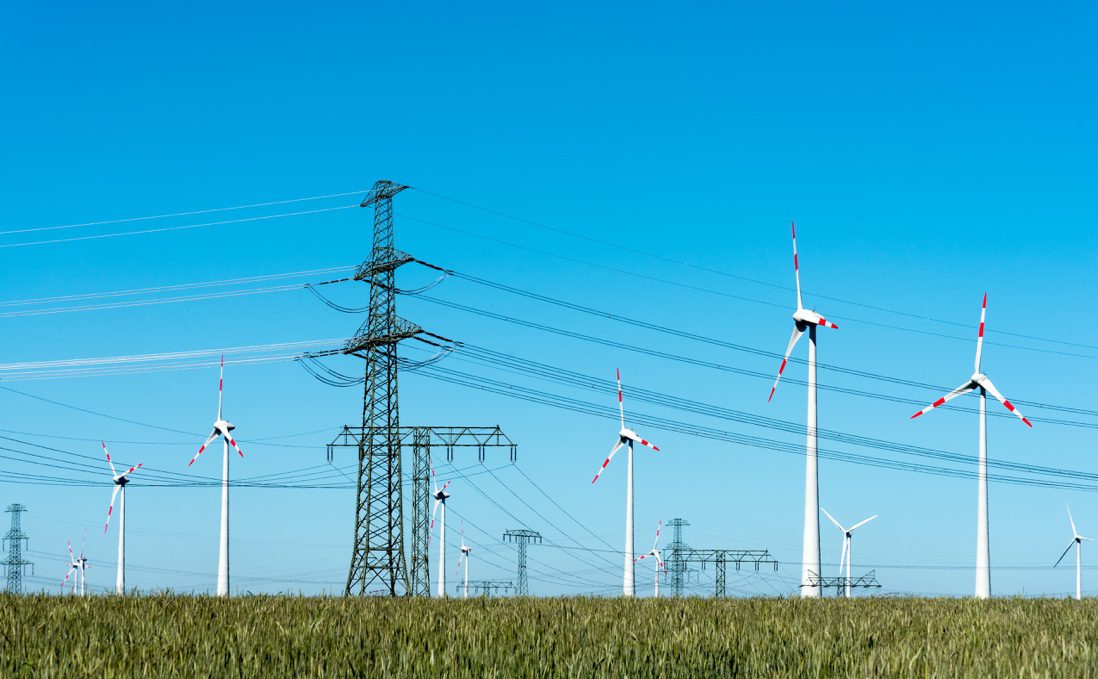 Wind turbines in a field against a blue sky.