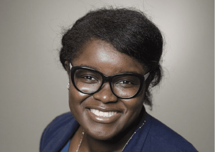 A woman wearing glasses smiles for the camera.