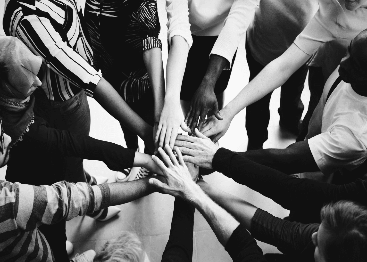 A group of people putting their hands together in a circle.