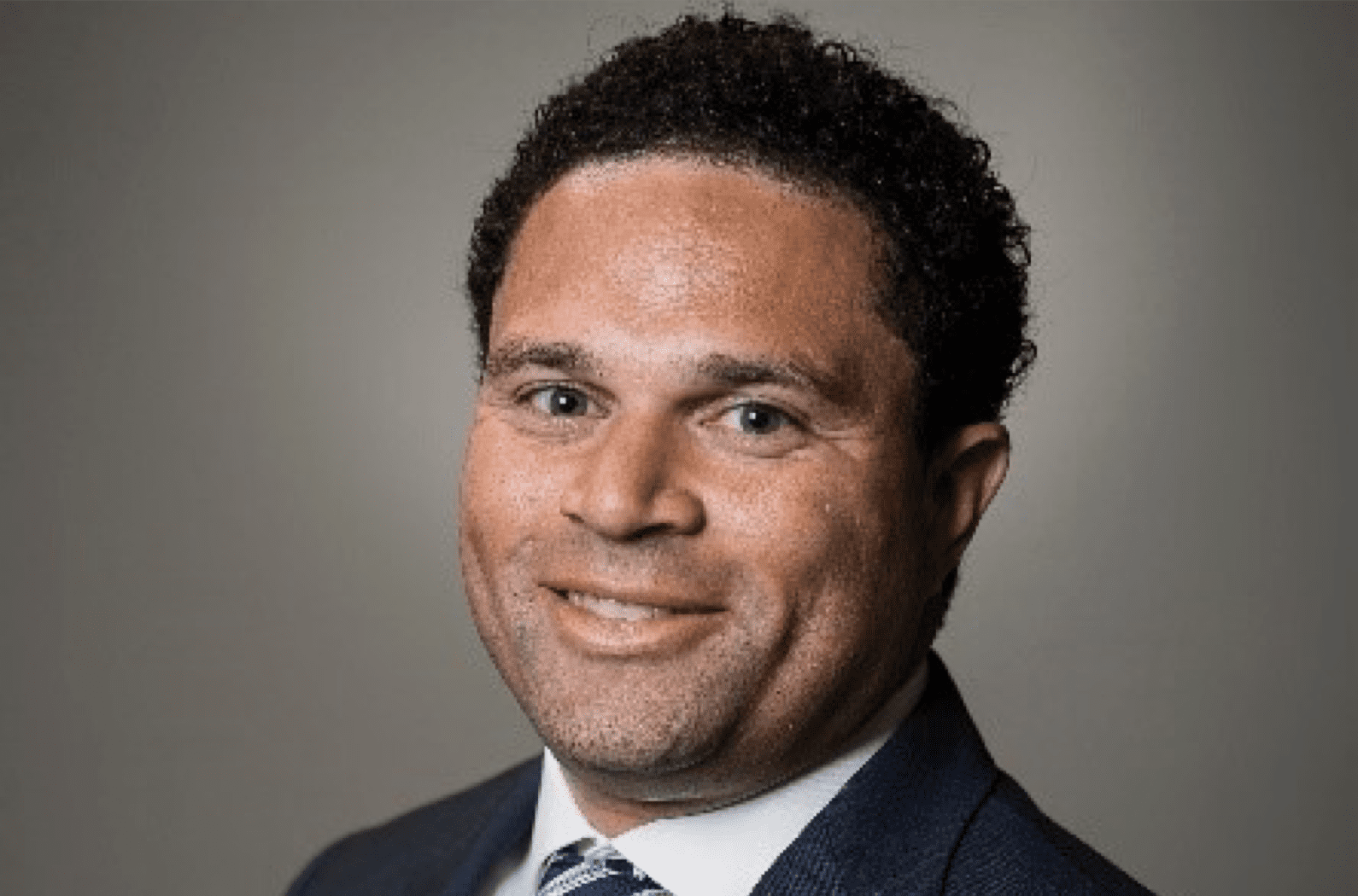 A man in a suit and tie smiles for the camera.