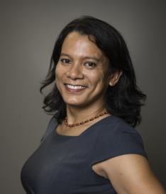 A smiling woman in a gray shirt.