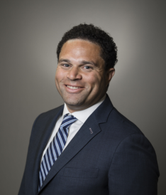 A man in a suit and tie smiles for the camera.