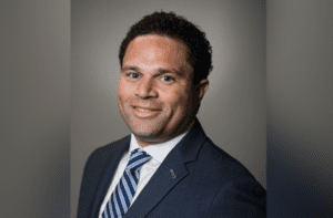 A man in a suit and tie smiling for the camera.