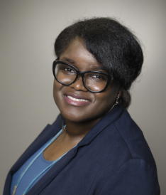 A black woman wearing glasses and a blue blazer.