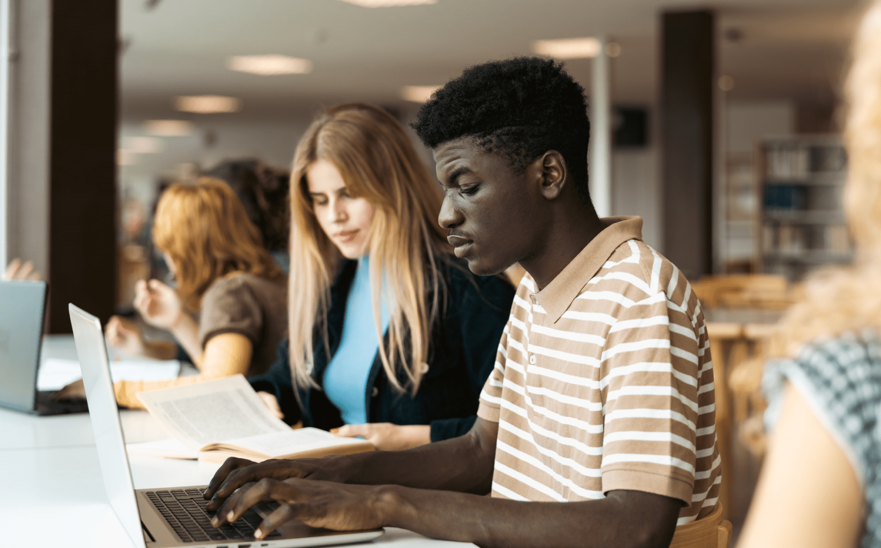 A group of students working on laptops in a library.