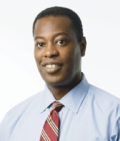 A black man in a blue shirt and red tie.